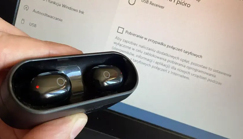 Słuchawki bezprzewodowe w etui, gotowe do połączenia z wieżą. Na ekranie komputera widać ustawienia urządzeń USB.