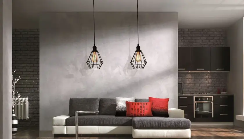 Nowoczesna kuchnia i salon rozdzielone betonową ścianą działową. Dwa wiszące lampy tworzą nastrój.