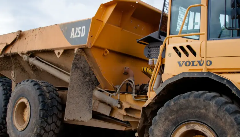 Żółte, masywne **Volvo wozidlo** budowlane z błotem na karoserii i oponach. Widoczna kabina i część skrzyni ładunkowej z oznaczeniem A25D.