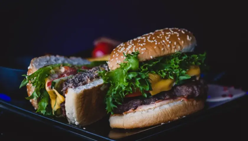 Pyszny kurczak burger mc, przekrojony na pół, z soczystą sałatą, serem i pomidorami.