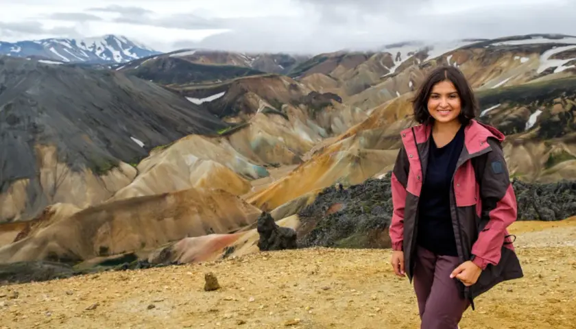Uśmiechnięta kobieta na tle barwnych gór Landmannalaugar na Islandii.