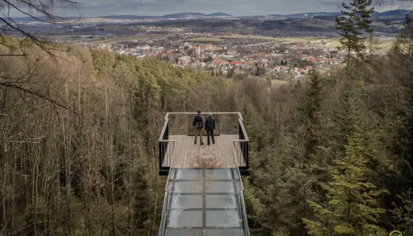 Dwie osoby stoją na szklanym tarasie widokowym, podziwiając panoramę Starego Sącza. To jedna z głównych atrakcji turystycznych regionu.