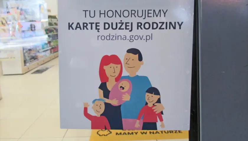 Tu honorujemy kartę dużej rodziny. Uśmiechnięta rodzina z dziećmi na plakacie.