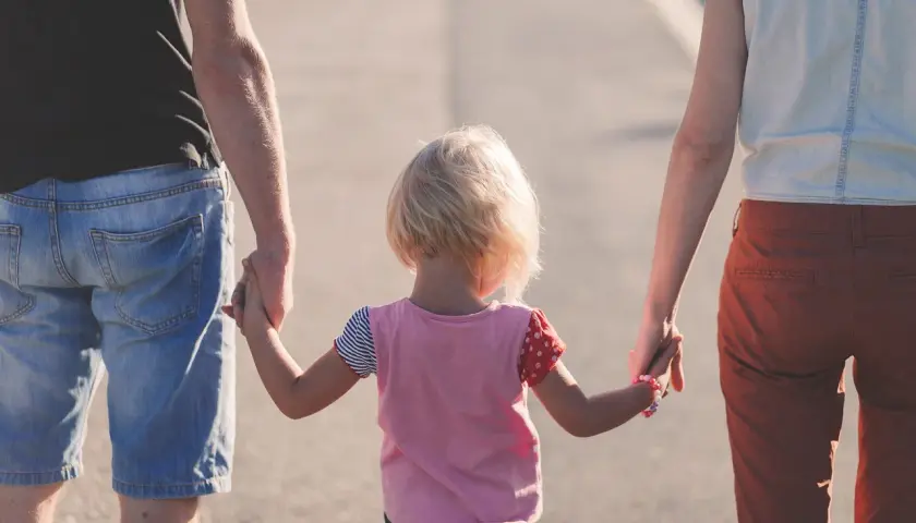 Rodzina idzie razem. Dziecko trzyma za ręce kobietę i mężczyznę, tworząc piękny związek z kobietą z dzieckiem.