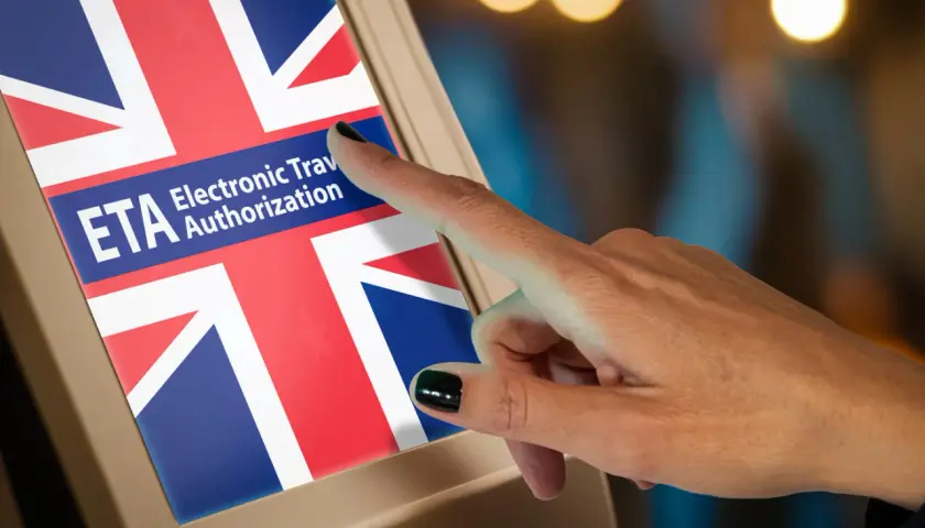 Dłoń dotyka ekranu z flagą Wielkiej Brytanii i napisem ETA Electronic Travel Authorization.