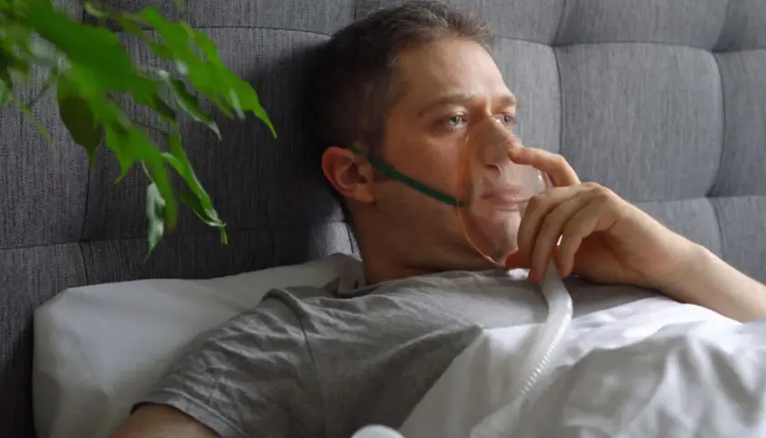 Mężczyzna w łóżku z maską tlenową, która pomaga mu oddychać. Sól fizjologiczna do inhalacji ułatwia mu powrót do zdrowia.