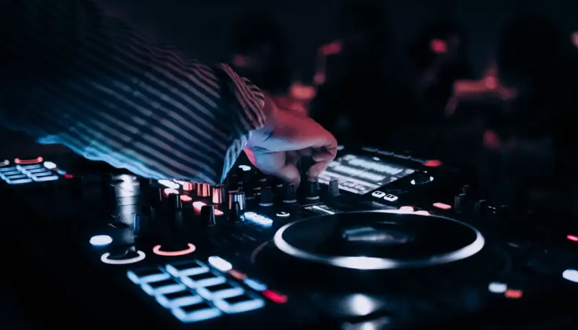 Dłoń DJ-a kręci gałką miksera, tworząc muzykę na wesele. Zastanawiasz się, ile kosztuje dj na wesele?