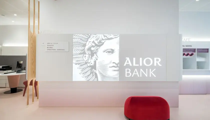 Nowoczesne wnętrze oddziału Alior Bank z logo banku, grafiką i czerwonym pufem.