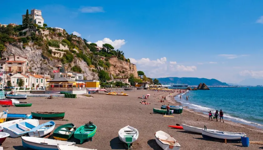 Spiagge Vietri sul Mare con barche sulla sabbia scura e case aggrappate alla scogliera.