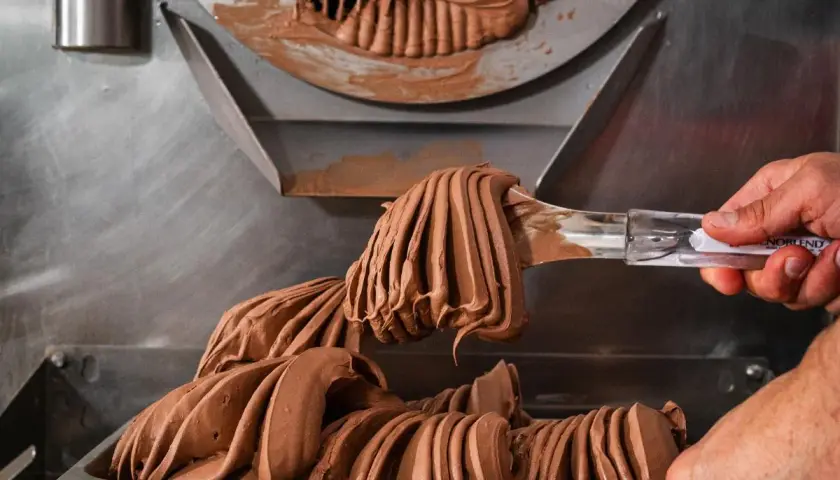 Gelato al cioccolato cremoso viene prelevato da una macchina, con destrosio additivo per la consistenza perfetta.