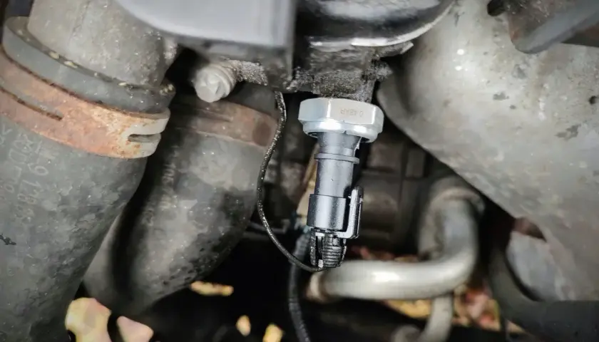 Czujnik ciśnienia oleju 2.0 TDI znajduje się w pobliżu metalowych rur i przewodów silnika.