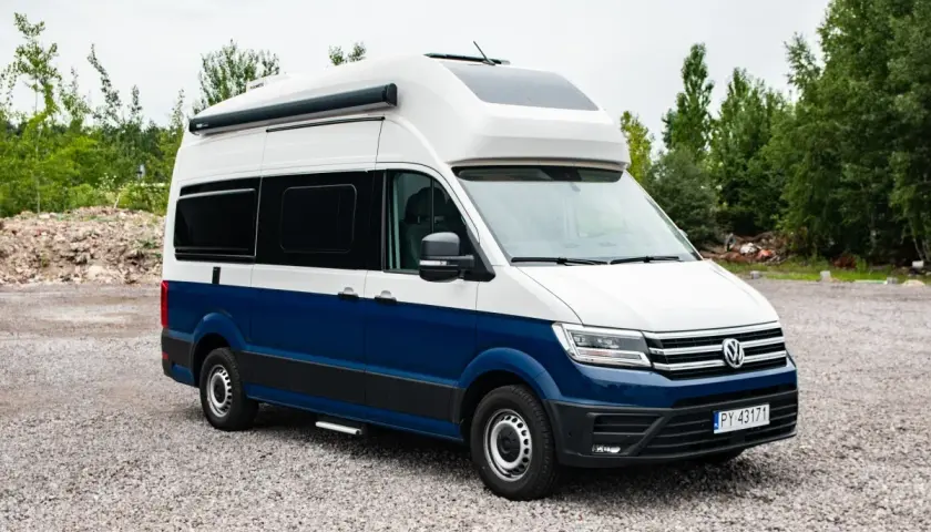 Nowoczesna produkcja kamperów: biało-niebieski Volkswagen Crafter z zabudową kempingową, gotowy na przygody.