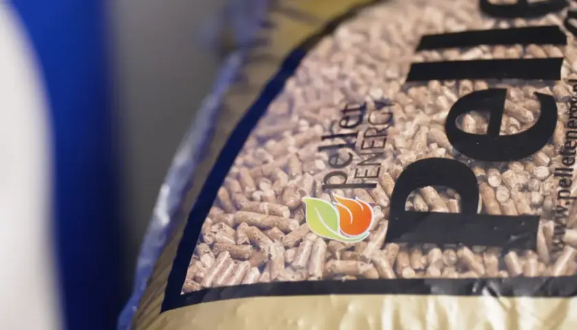 Zbliżenie na worek z pelletem drzewnym. Logo "Pellet Energy" i płomień z liściem. Dowiedz się, jak zrobic pellet.