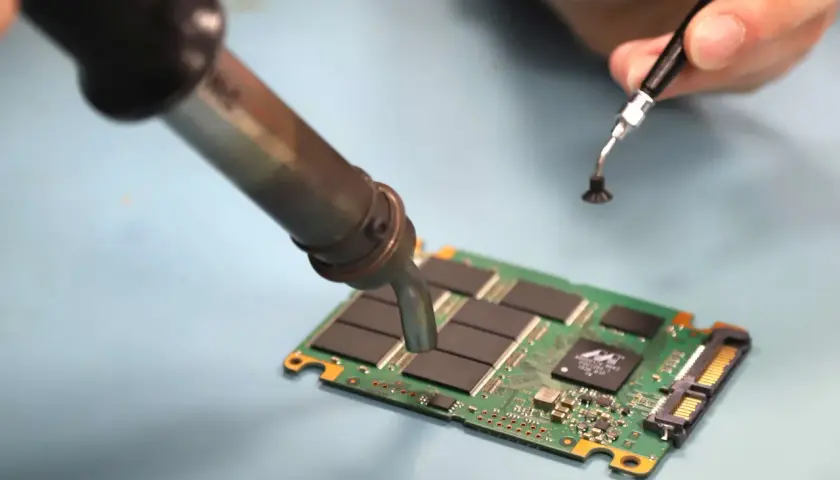 Reparatur einer SSD. Ein Lötkolben erwärmt die Platine, um mögliche ssd defekt symptome zu beheben.
