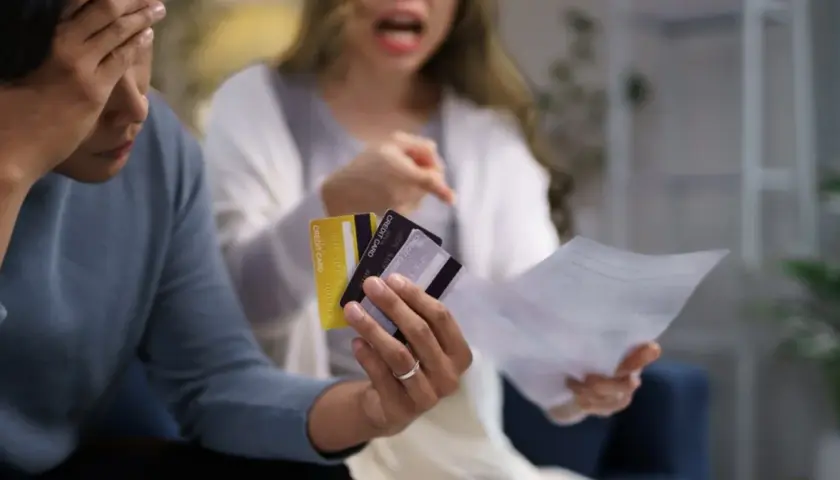 Kłótnia o finanse. Czy mąż powinien dawać żonie pieniądze? Para z kartami kredytowymi i rachunkami w rękach.