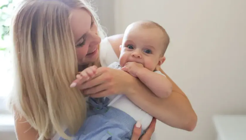 Uśmiechnięta mama tuli dziecko. To piękny widok, jakby właśnie otrzymała becikowe dla kogoś tak cudownego.