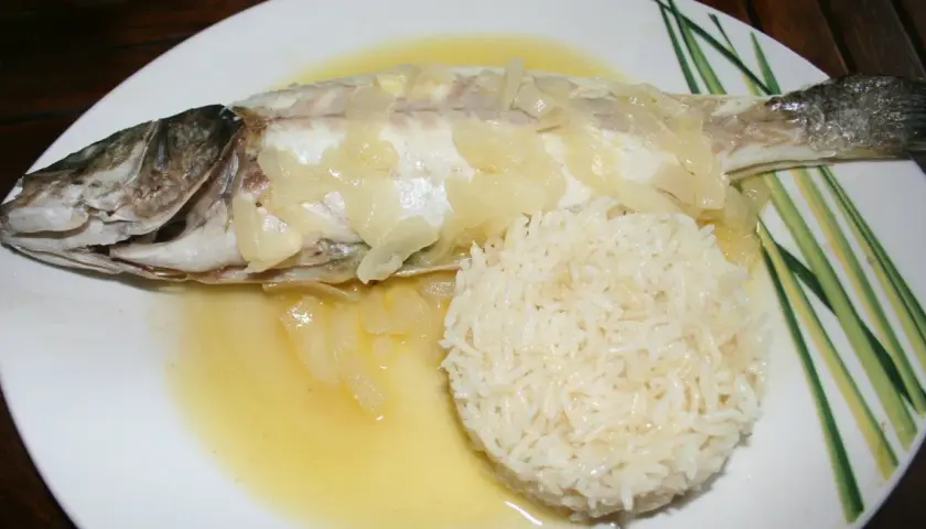 Un délicieux filet de loup au four, nappé d'une sauce au vin blanc et accompagné de riz.