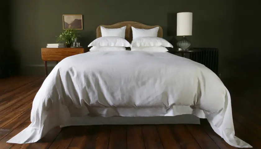 A white duvet cover, resembling a plush bedspread, drapes over a neatly made bed, contrasting with the crisp bed sheet visible beneath.