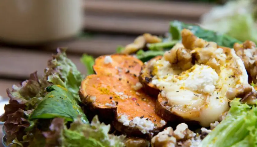 Deliciosa ensalada de batata asada con queso de cabra cremoso, nueces crujientes y hojas verdes frescas.