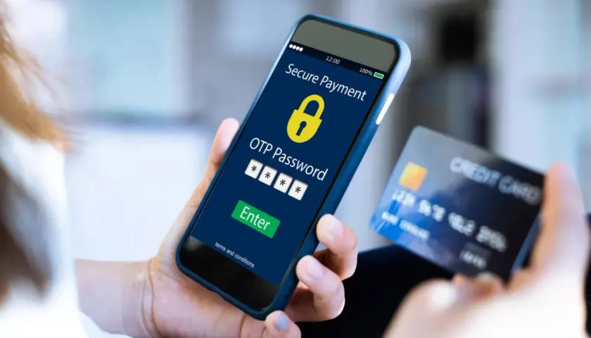 Mano sostiene un teléfono con pantalla de pago seguro y código OTP, junto a una tarjeta de crédito. El **sms certificado** confirma la transacción.