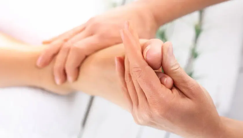 Dłonie wykonujące masaż stopy, rehabilitacja po operacji.