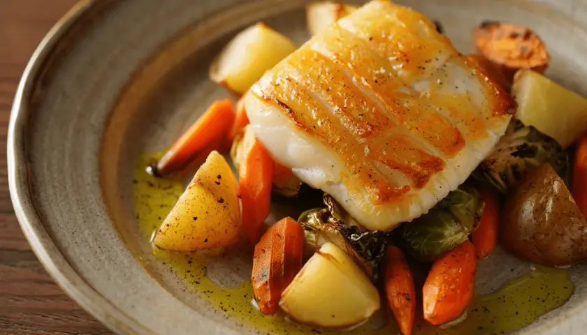 Filete de bacalao dorado con patatas y zanahorias asadas, una deliciosa forma de como hacer bacalao.