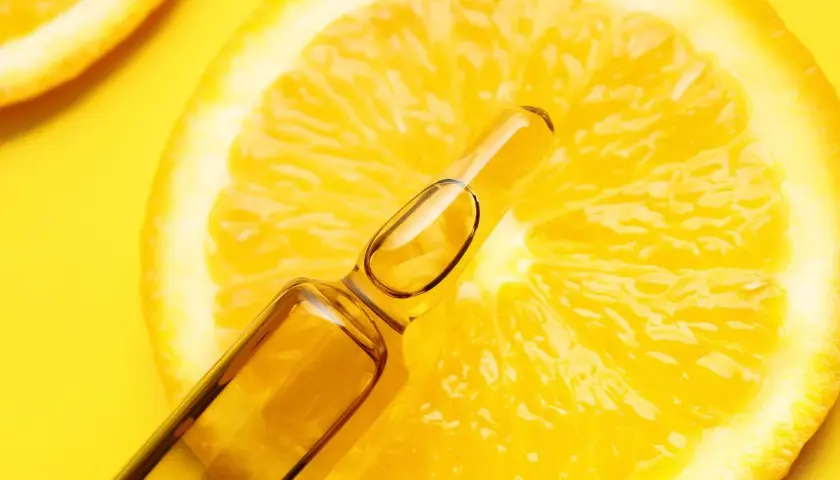 Fetta di limone brillante con fiala di siero alla vitamina C, un concentrato di freschezza e benessere.