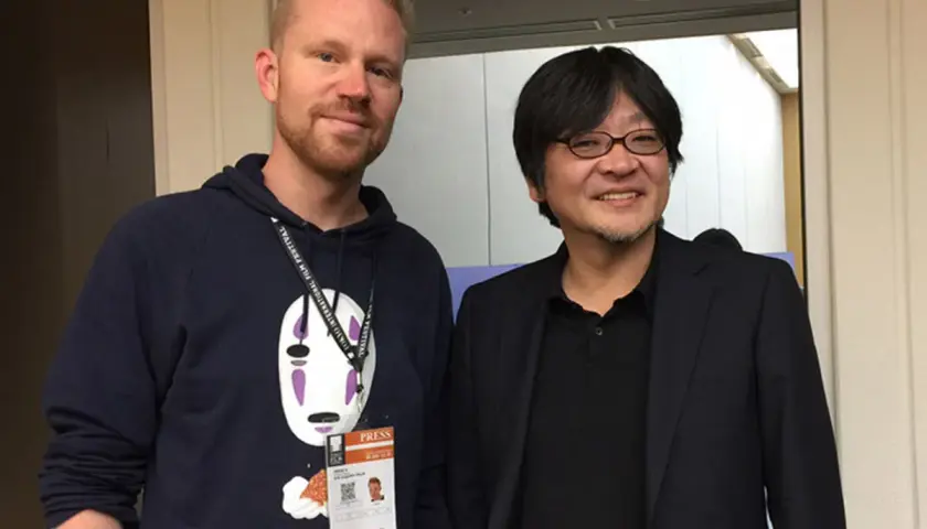 Erik Augustin Palm med en pressackreditering och en tröja med No-Face från Spirited Away, bredvid en japansk man i kostym.