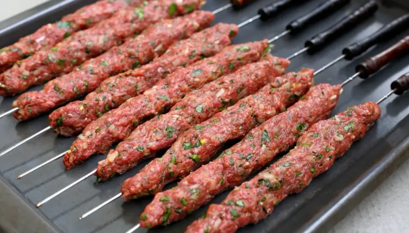 Rå irakisk kebab på spett, redo för grillen. Kryddad färs med lök och örter.