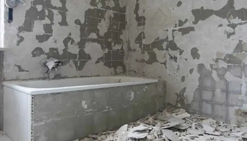 Łazienka w trakcie remontu, z odsłoniętymi ścianami i gruzem.