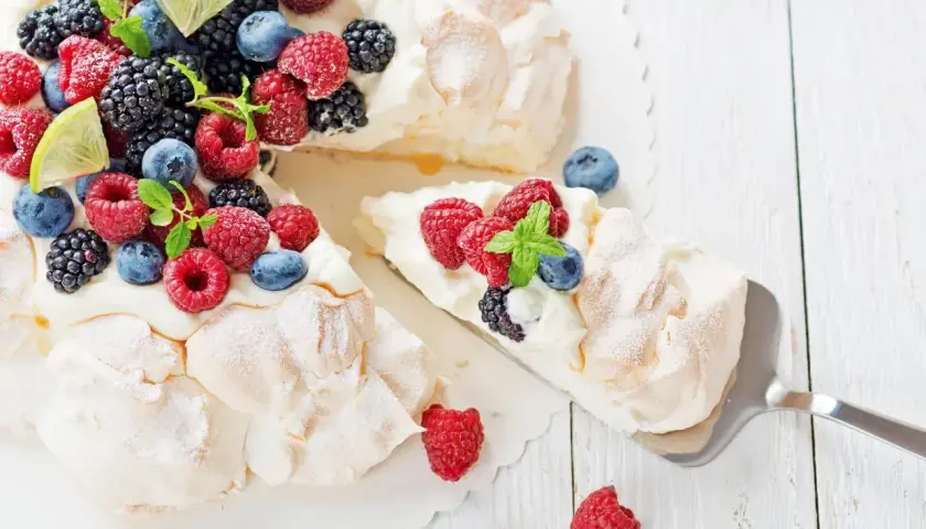 Beza pavlova która zawsze wychodzi, udekorowana świeżymi malinami, borówkami, jeżynami i plasterkami limonki.