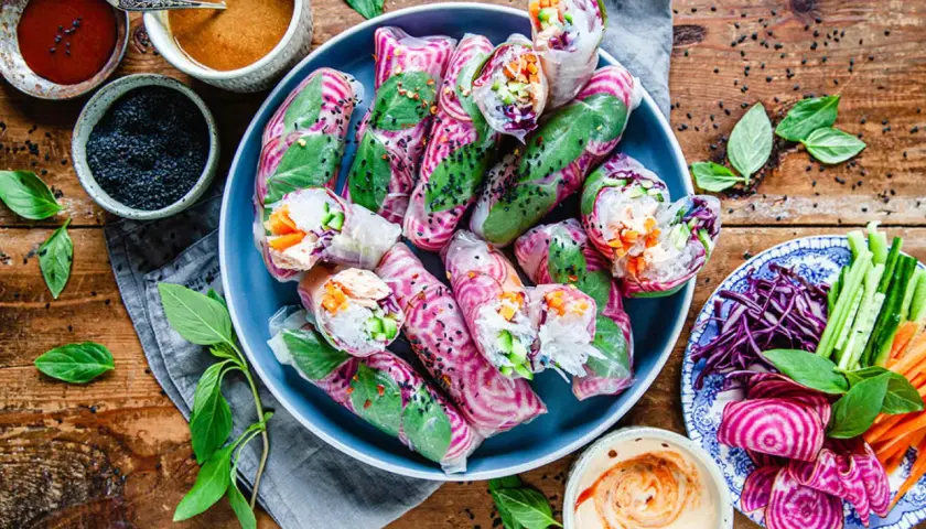 Vackra vietnamesiska vårrullar med kyckling, färska grönsaker och en krämig dippsås. Serveras med en sidoplatta av grönsaker och rödbetor.