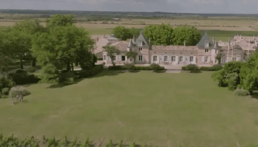 Un magnifique château bordelais, typique de la route des châteaux du Médoc, se dresse au milieu de vignes et d'arbres verdoyants.