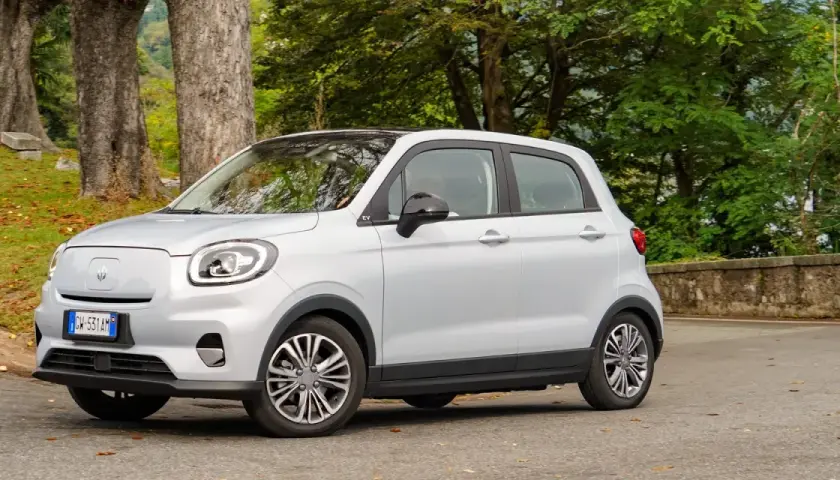 Leapmotor T03 usata, un'auto elettrica compatta e agile, parcheggiata in un contesto naturale con alberi e foglie autunnali.