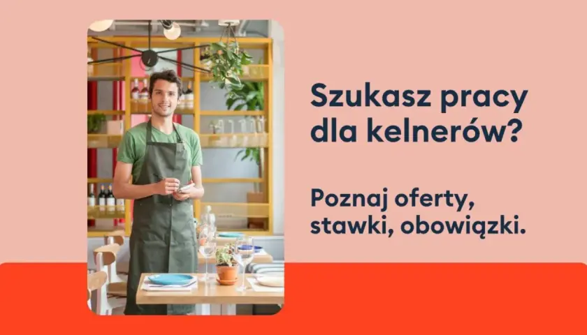 Uśmiechnięty kelner w fartuchu stoi w restauracji, gotowy przyjąć zamówienie. Szukasz pracy dla kelnerów?