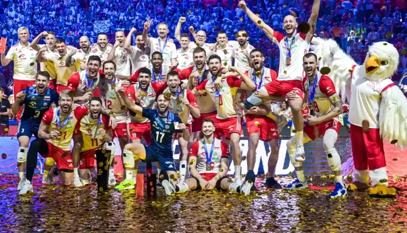 Radosna drużyna siatkarzy świętuje, kiedy Polska była mistrzem świata w siatkówce. Konfetti i maskotka orła dopełniają scenę triumfu.
