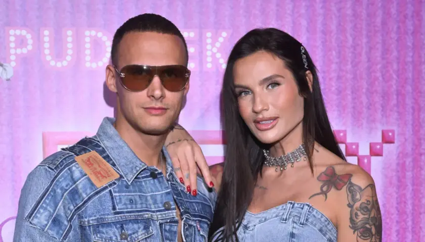 Mateusz Świerczyński z Love Island w dżinsowej kurtce i jego partnerka z naszyjnikiem na tle różowej ściany.
