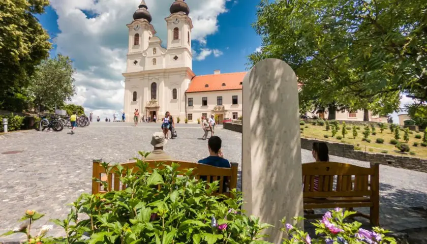 Tihany Balaton: malowniczy plac przed opactwem benedyktynów, z turystami odpoczywającymi na ławkach i podziwiającymi architekturę.