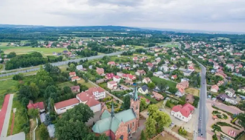 Widok z lotu ptaka na Wola Rzędzińska: kościół, domy, droga i tereny zielone.