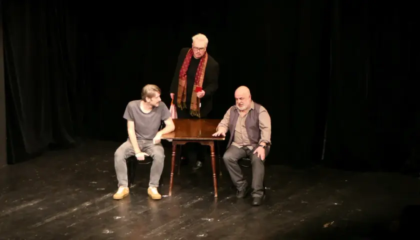 Trzej mężczyźni na scenie Teatru Korez, Plac Sejmu Śląskiego Katowice. Jeden stoi, dwóch siedzi przy stole.