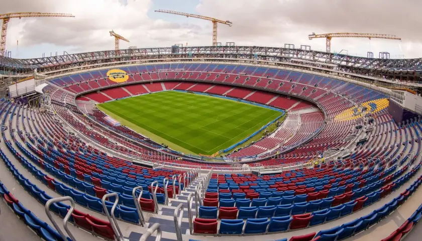 Stadion Camp Nou w trakcie przebudowy, z widocznymi dźwigami i częściowo pustymi trybunami.