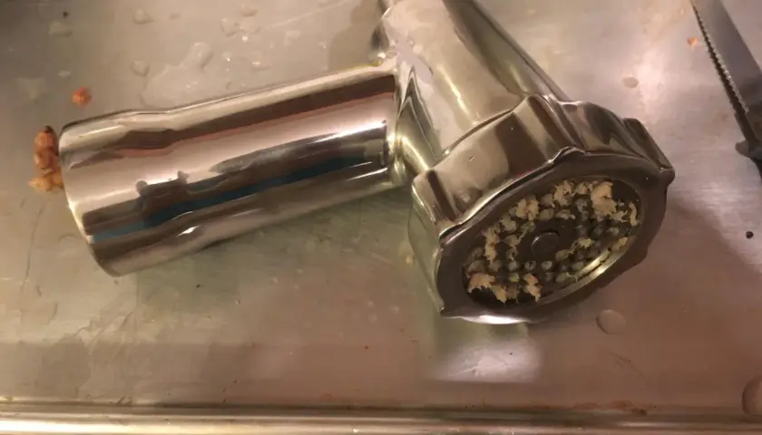 Metalowa maszynka do mielenia mięsa, przypominająca syberyjski młynek, z resztkami mielonego mięsa.