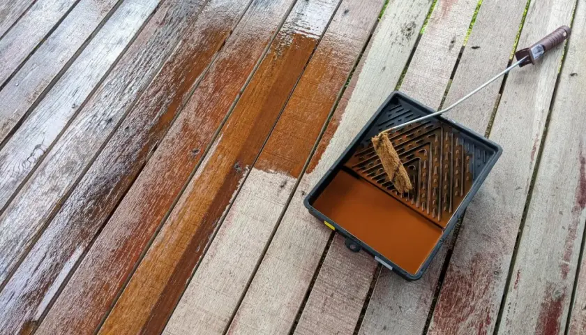 Malowanie boazerii na tarasie. Drewno odzyskuje blask dzięki brązowej lazurze.