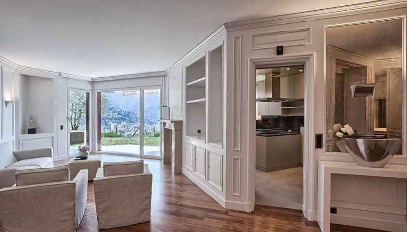 Soggiorno elegante con camino, divani, vista panoramica e cucina moderna. Le pareti in cartongesso effetto legno creano un'atmosfera calda e accogliente.