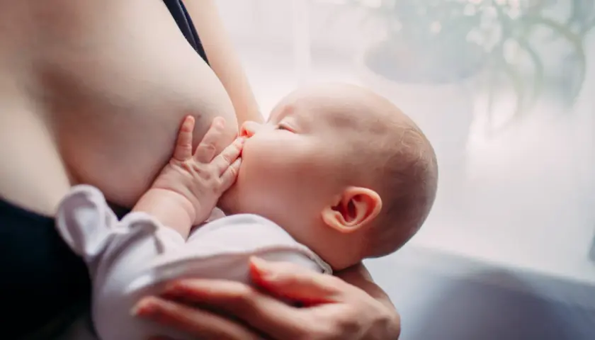 Un neonato si nutre al seno. Scopri come aumentare il latte materno in modo naturale per il benessere del tuo bambino.