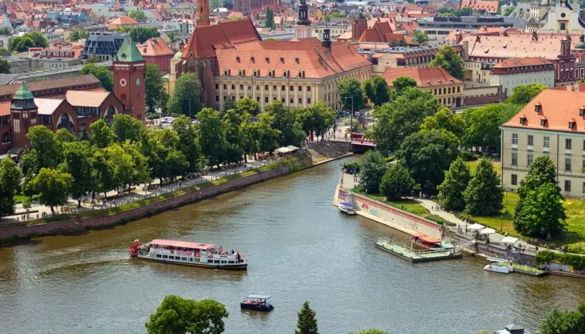 Wrocław inwestycje: malowniczy widok na Odrę z zabytkową architekturą i statkami wycieczkowymi.