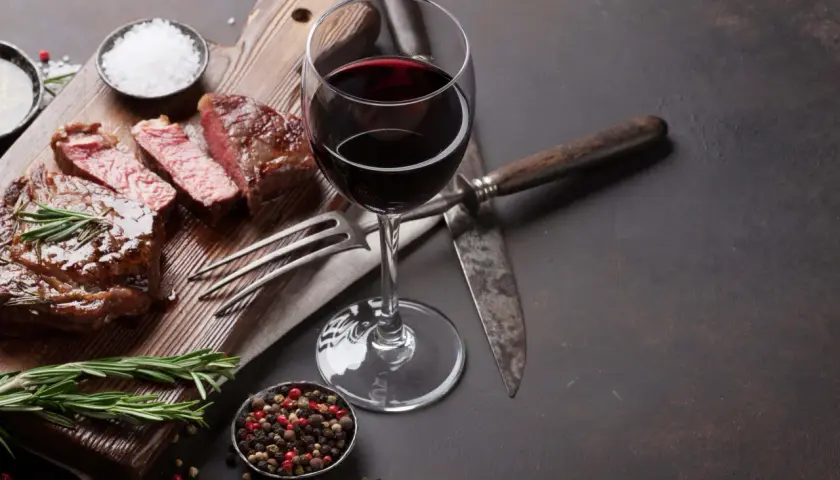 Un verre de vin malbec, parfait pour accompagner ce steak juteux. Une dégustation qui évoque la richesse d'une belle région viticole.