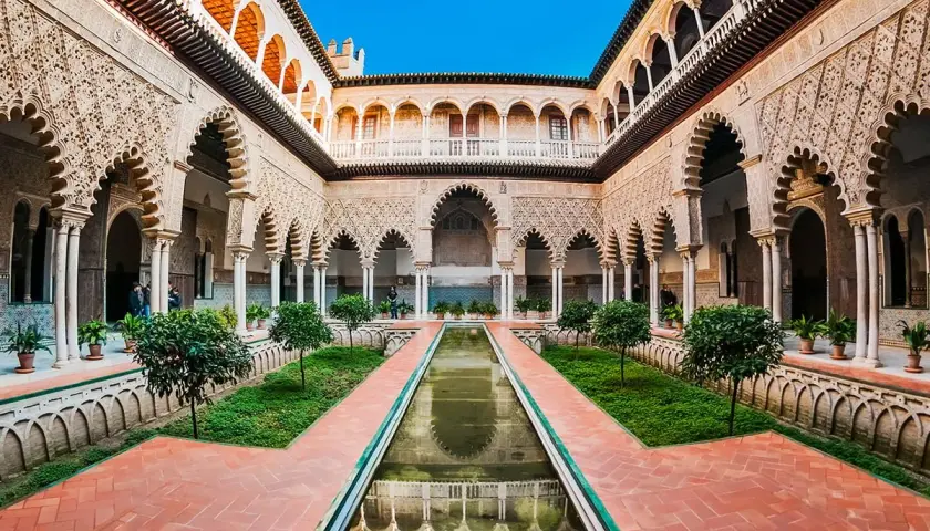Wspaniały dziedziniec Alcazar z basenem, zielenią i misternymi łukami.