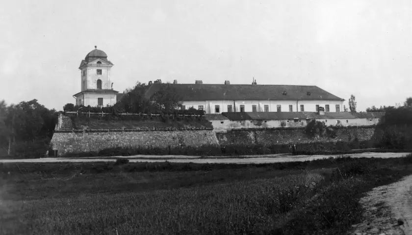 Zamek w Rzeszowie z wieżą i długim budynkiem, otoczony kamiennym murem.