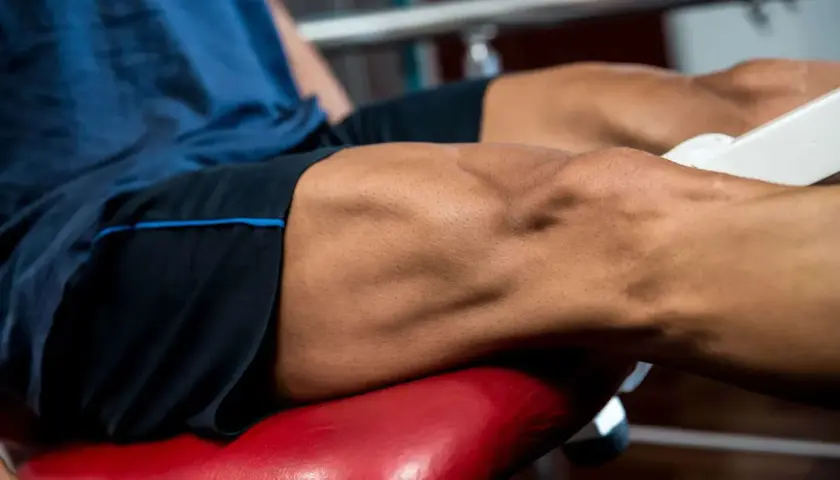 Primer plano de un hombre realizando ejercicios para cuadriceps en una máquina de gimnasio.